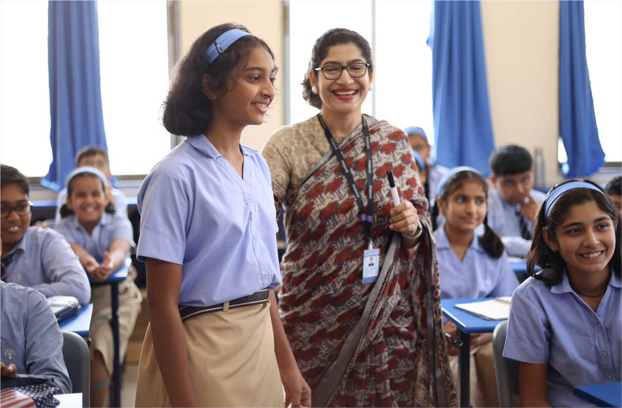 A teacher engaging warmly with students in the classroom, building trust, communication, and a positive learning environment