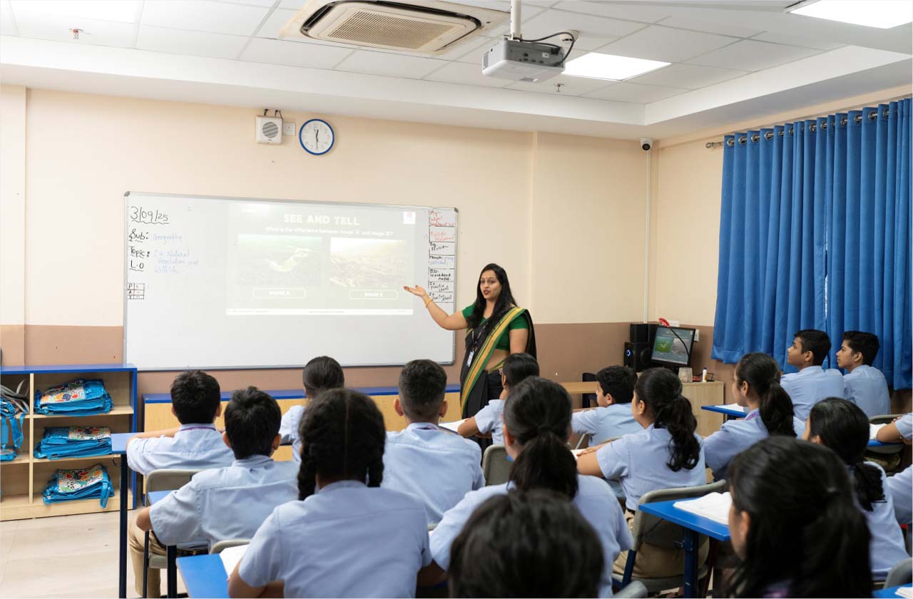 A teacher interacting warmly with students in a supportive classroom, showing student well-being, confidence, emotional safety, and positive teacher-student relationships.