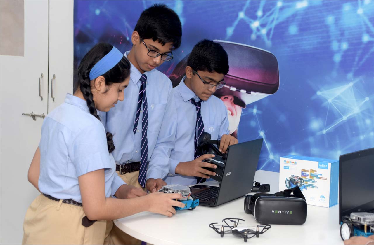 A group of school students exploring animation, gaming, and visual media using computers and tablets in a modern classroom.